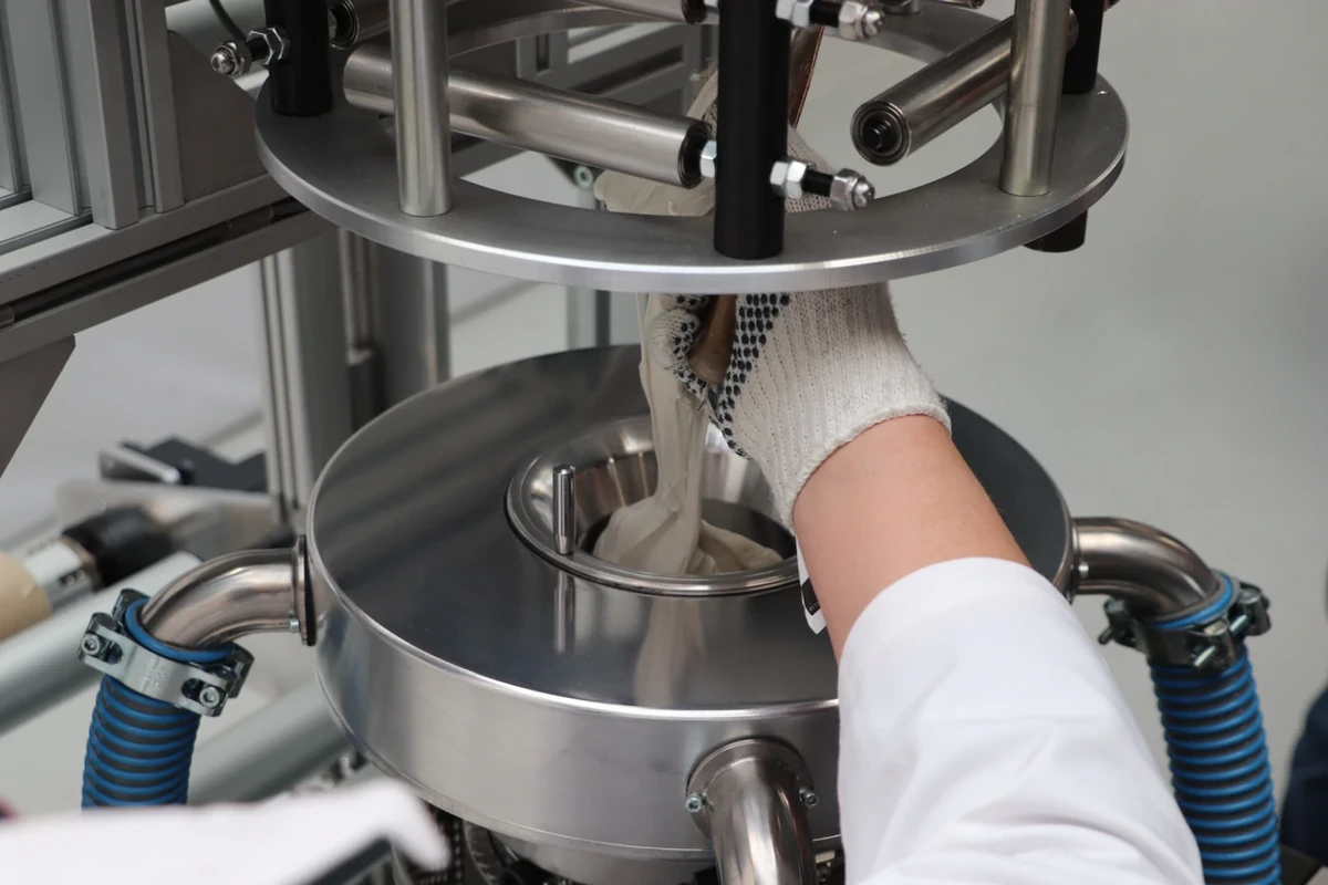 Operator loading polymer granules into a LabEx 25-3 material hopper before a test run